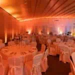 Uređena dvorana za proslave i poslovne evente s elegantnim stolovima i osvjetljenjem.