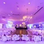 Sadržaj za ALT: Prostrana dvorana za evente s ukrašenim stolovima i cvjetnim aranžmanima.