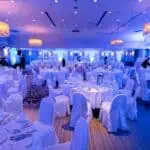 Osvijetljena dvorana za evente s modernim dekorom i stolovima za svečane prigode.