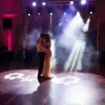 Par se ljubi na plesnom podiju pod svjetlima i dimom.